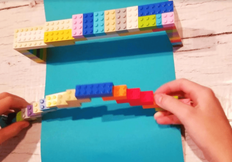 child's hands holding a bridge made of building blocks