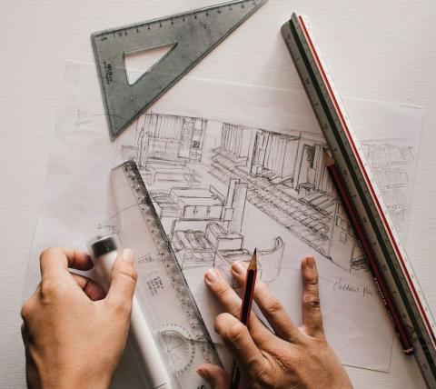 2 hands, with pencils, rulers, and a triangle drawing blueprints