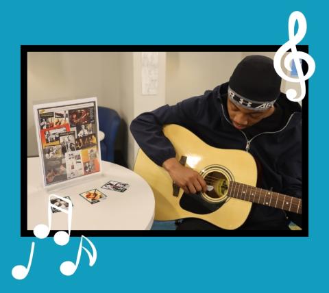 Young man playing a guitar next to a table