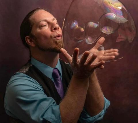 a photograph of magician River Barry blowing bubbles