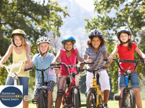 five children wearing bikes helmet sitting on bikes outside
