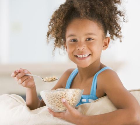 smiling african american girl eating a bowl of cereal