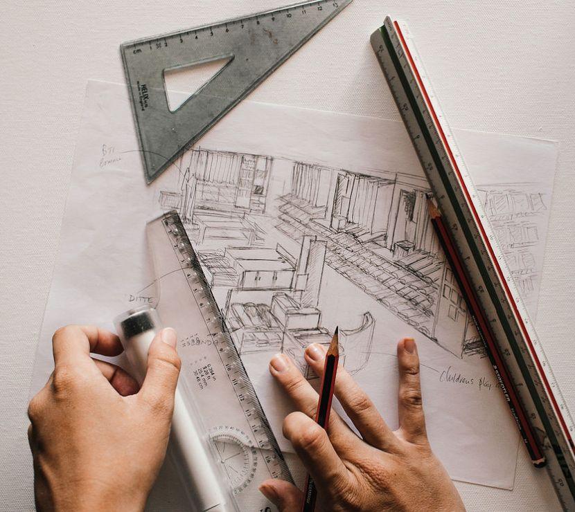 2 hands, with pencils, rulers, and a triangle drawing blueprints